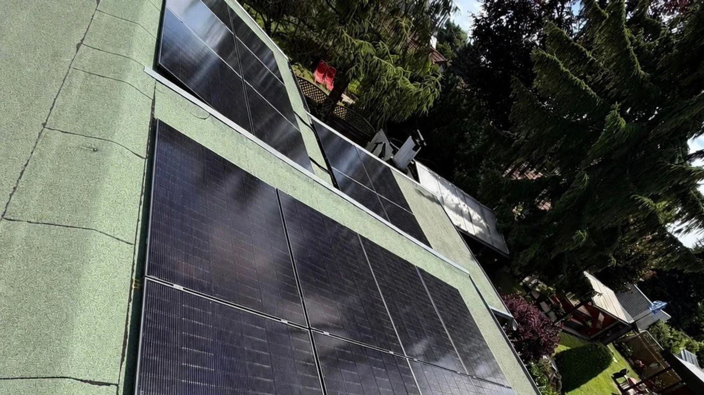Solaranlage auf einem Dach, unmittelbar angrenzend hohe Bäume, die bei tiefem Sonnenstand Schatten auf die Module werfen können
